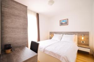 a bedroom with a white bed and a desk and a window at Dok Apartment in Petrcane
