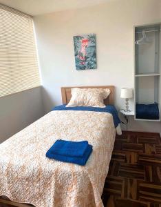 Un dormitorio con una cama con toallas azules. en Pershing, lindo dpto. amoblado c/3 dorm y wifi., en Lima