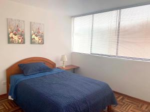 Un dormitorio con una cama azul y una ventana en Pershing, lindo dpto. amoblado c/3 dorm y wifi., en Lima