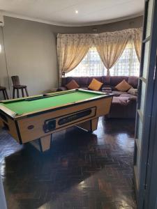 a living room with a pool table and a couch at Palm Guesthouse in Zeerust