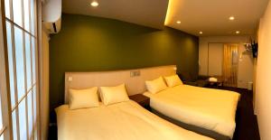 two beds in a room with green walls and windows at Gion Shirakawa - Vacation STAY 24781v in Kyoto