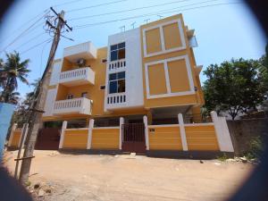 a yellow and white house with a fence at Cheerful 2-bedroom near Auro Beach in Kālapettai