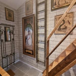 un escalier avec des peintures et des photos sur un mur dans l'établissement La cabane des sorciers, à Liévin