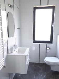 a white bathroom with a sink and a toilet at Apartamenty Pod Sosnami in Sarbinowo