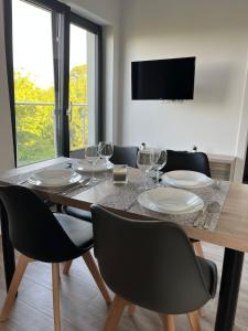 una sala da pranzo con tavolo, sedie e bicchieri da vino di Apartamenty Pod Sosnami a Sarbinowo