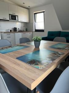 una cucina con tavolo in legno e pianta in vaso di Apartamenty Pod Sosnami a Sarbinowo