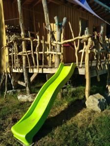 een groene glijbaan voor een houten huis bij Gîte nature Au pied des hêtres in Vitrac-sur-Montane