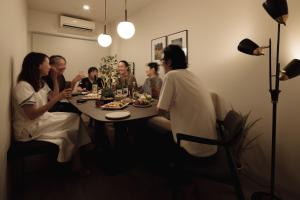 un groupe de personnes assises autour d'une table à manger dans l'établissement Good Neighbors, à Kanazawa