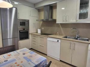 a kitchen with white cabinets and a table and a sink at Roses Casc Antic SL Sant Elm 4 in Roses