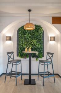 a table with three chairs and a green wall at Hotel Lloret Santa Rosa by Pierre & Vacances in Lloret de Mar