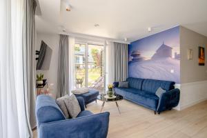 a living room with a blue couch and a bed at Śnieżka Exclusive Apartamenty in Kowary