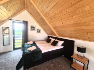 un lit dans une chambre avec un plafond en bois dans l'établissement Zacisze Mazurskie, à Ryn