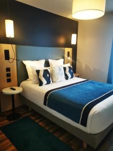 a bedroom with a large bed with blue sheets and pillows at Residhome Asnieres in Asnières-sur-Seine