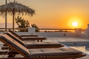 een groep ligstoelen naast een zwembad met zonsondergang bij Golden Sand Villas with Private Pool in Vívlos