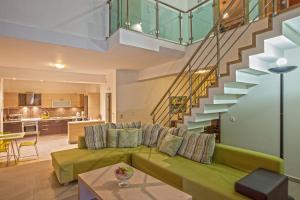 a living room with a green couch and a staircase at Salvia Villas in Skouloúfia