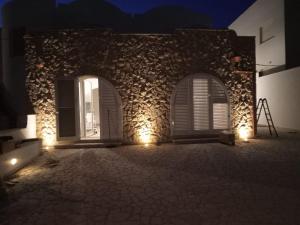 un edificio de piedra con 2 ventanas y luces en VILLA DEI GIGLI PESCOLUSE, en Marina di Pescoluse