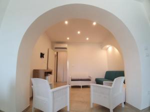 una sala de estar con un arco y sillas blancas en VILLA DEI GIGLI PESCOLUSE, en Marina di Pescoluse