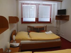 a bedroom with a bed and a desk and windows at Hotel Garni VŠB in Ostrava