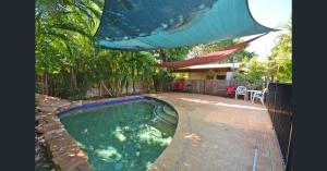 a swimming pool in a backyard with an umbrella at Kirei Pearl Accommodation Broome in Broome