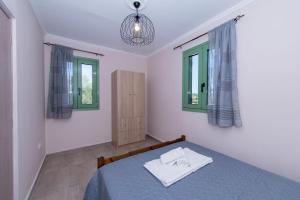 a bedroom with a blue bed and two windows at Mariettas Cottage in Pigadhákia
