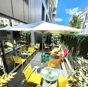d'une terrasse avec des tables, des chaises et un parasol. dans l'établissement Residhome Asnieres Park, à Asnières-sur-Seine