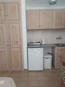 a kitchen with a white refrigerator and wooden cabinets at Nicolas Apartments in Ierapetra