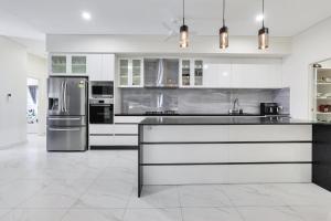 a kitchen with white cabinets and a stainless steel refrigerator at Ravi’s Home in Berrimah