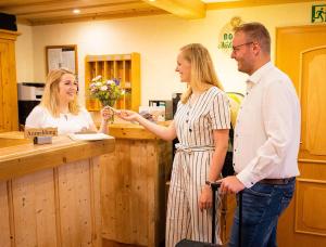 Ein Mann und zwei Frauen stehen an einer Kasse in der Unterkunft Landgasthaus Steffes Hof in Bad Berleburg