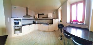 duża kuchnia z białymi szafkami i drewnianą podłogą w obiekcie Gîte Lilas, LOFT 2 à 8 personnes, avec salle de jeux et SPA dans la résidence w mieście Ventron