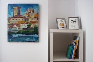 un dipinto appeso a un muro accanto a uno scaffale con dei libri di ROMÁNICO CENTRO a Zamora