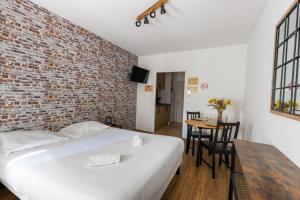 1 dormitorio con cama blanca y pared de ladrillo en Studio Elément - Feu, en Saint-Aignan