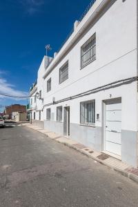 a white building with two garage doors on a street at Algaba aral in Alcalá del Río