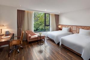 Habitación de hotel con 2 camas, escritorio y silla en Ravatel Home Bac Giang en Bắc Giang