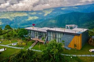 uma casa numa colina com montanhas ao fundo em SaffronStays Glasshouse Celeste, Ranikhet - luxurious glass villa with breathtaking views em Bhatrojkhan