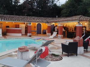 een huis met een zwembad en stoelen en een tafel bij Le Clos de L'Isle in Arles