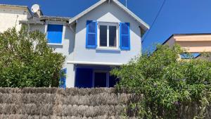 a white house with blue shutters and a fence at LES PAQUERETTES in Larmor-Plage