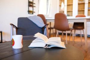 リュブリャナにあるThe Modern & Comfortable Apartmentのコーヒーカップ付きテーブルの上のオープンブック