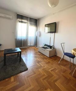 a living room with a table and a tv on the wall at Stan na dan u centru, Inđija in Inđija