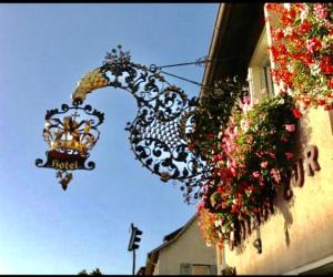 un panneau de paon sur le côté d'un bâtiment avec des fleurs dans l'établissement Hotel Krone, à Neuenburg am Rhein