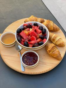 um prato de comida com uma taça de frutas e croissants em Midgard Suites (Medieval Town) in Ilha de Rhodes