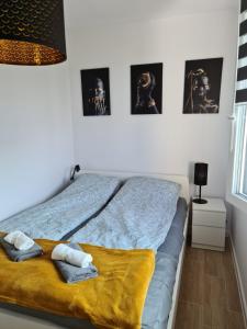 a bed with two towels and pictures on the wall at Apartamenty "Aga" Rusinowo in Rusinowo