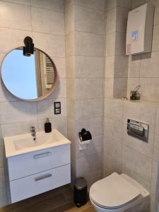a bathroom with a sink and a toilet and a mirror at Apartamenty "Aga" Rusinowo in Rusinowo