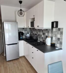 a kitchen with white cabinets and a white refrigerator at Apartamenty "Aga" Rusinowo in Rusinowo
