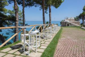 a row of white stools on a path next to the water at AH Premium Baia dei Faraglioni in Mattinata