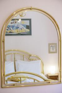 espejo de oro sobre una cama con almohada blanca en Gold n Blu Petalidi en Petalidhion
