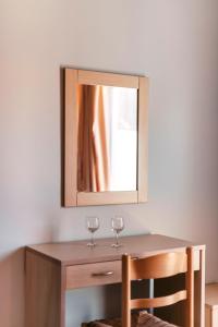 two wine glasses on a wooden table with a mirror at F.D.STUDIOS in Lardos