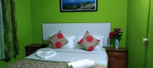 Dormitorio verde con cama blanca y almohadas rojas en Beverly Hills Home stay, en Darjeeling