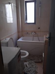 y baño con bañera, aseo y lavamanos. en Apartment with barbecue 1 km beach, en Atenas