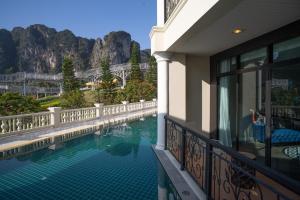 a swimming pool outside of a building with mountains in the background at Heaven View Krabi SHA in Ao Nam Mao