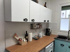 a kitchen with white cabinets and a wooden counter top at Piso completo a 5 minutos del metro linea 5 verde in Madrid